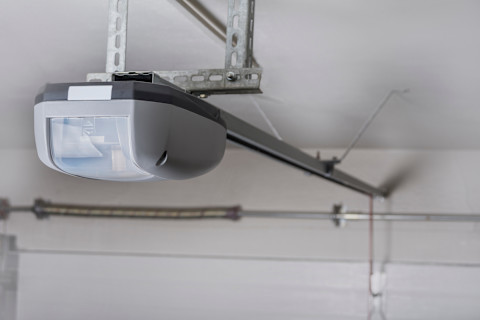 A closeup of an electric garage door opener installed in a garage.