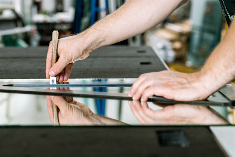 A professional is cutting some mirror glass to size.