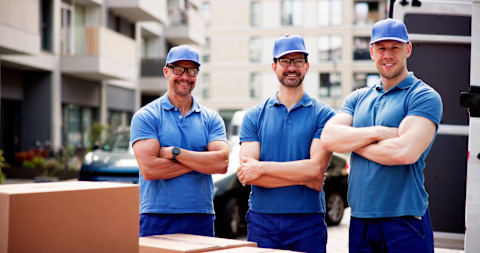 Three professionals are standing by moving boxes.