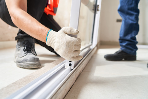 Closeup of two workers installing a window on a frame.
