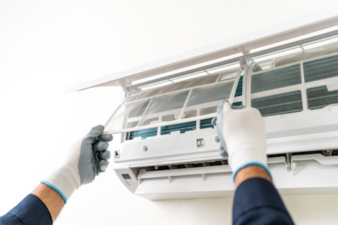Hands repairing an air conditioner