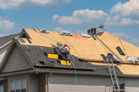 This image shows roofers installing or replacing a roof on a residential home.