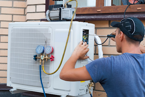 This image shows a tradesperson fixing a heating and cooling system.