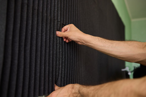 A pro installs soundproofing panels on a wall.