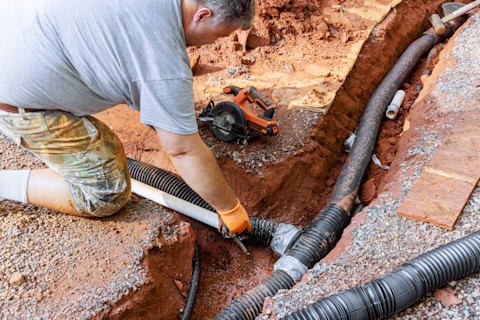 A man is installing a new drainage system into a house.