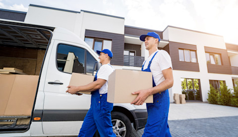 Two professionals are moving boxes into a van.