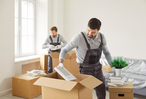 Two professionals are busy packing up some moving boxes.