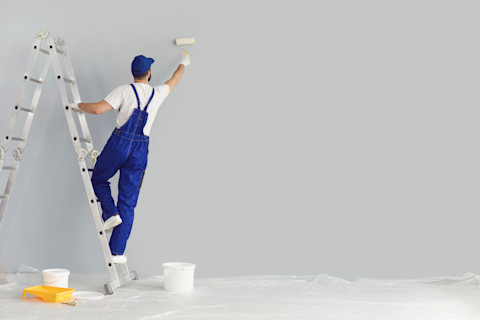 Painter on a ladder painting the wall
