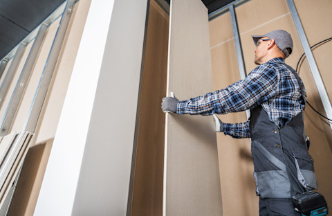 A man is installing drywall into a new home.
