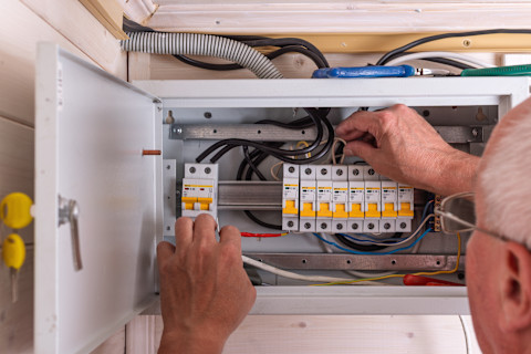 A technician adjusts a circuit breaker in an electrical panel.
