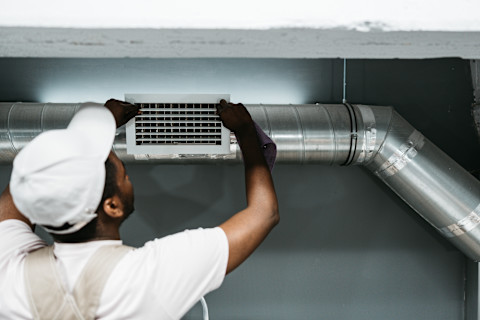 A tradesperson is clearing out an air duct.