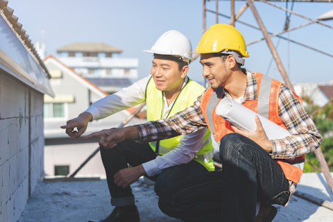 This image shows a general contractor wearing a high visibility vest and hard hat as he looks over floorplan details.