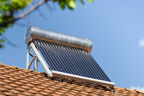 This image shows a solar water heater on top of the rooftop of a residential home.