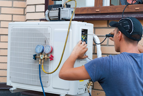 This image shows a tradesperson fixing a heating and cooling system.