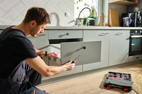 A man is testing a new kitchen cabinet.