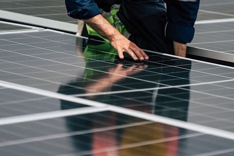 A pro installs solar panels on a roof.