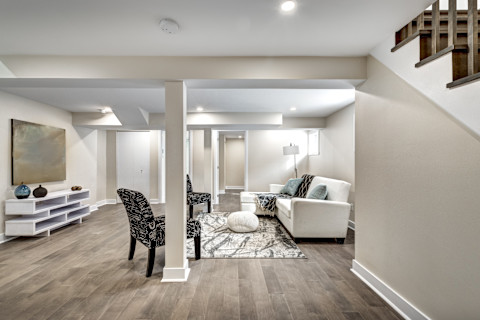 Wide shot of a finished basement with a black stone fireplace.