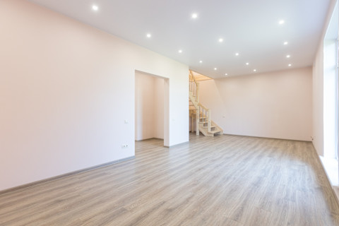 An empty, modern finished basement with laminate flooring.