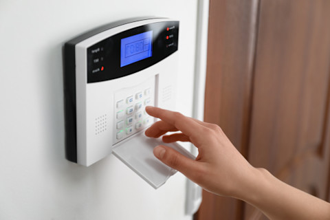 This image shows a person pressing the buttons on an electric security alarm keypad.