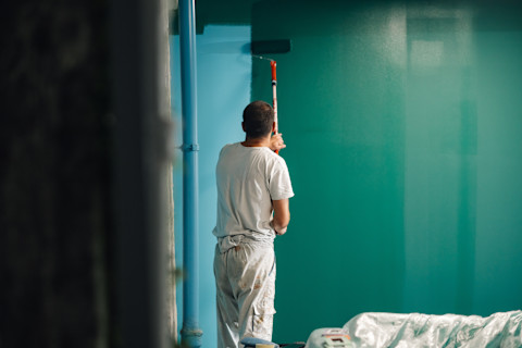 A man is adding a fresh layer of paint to inner walls.