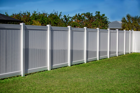 A white vinyl privacy fence surrounds a residential property. The solid panels create a clean and uniform boundary.