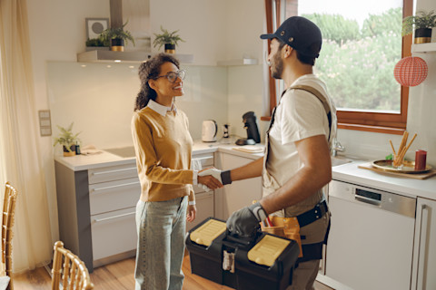 A lady looks happy with the service a handyman has provided.