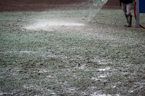 This image shows a landscaping tradesperson using a hose to hydroseed a patch of soil.