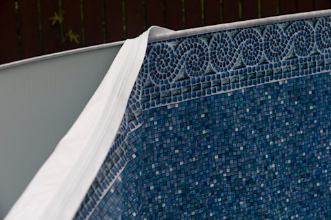 This image shows a pool liner that is partially attached to the interior of a pool. The liner features a mosaic-like design in a few shades of dark blue.