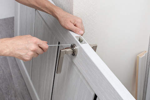 A worker installs a handle on a door using a screwdriver.