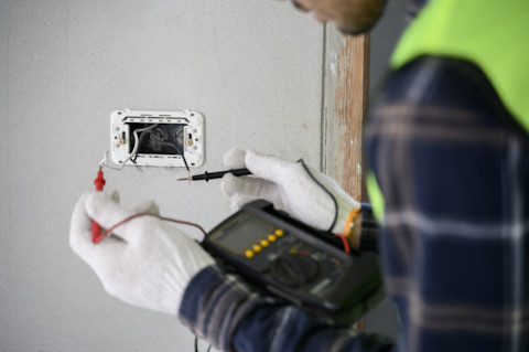 Electrician house construction worker using voltmeter check electric wire that been prepared.