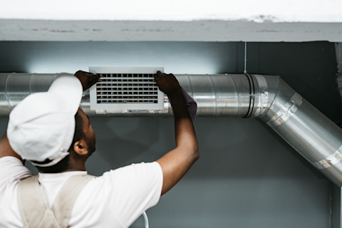 A tradesperson is clearing out an air duct.