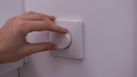 Electrician installing a white wall switch with screwdriver in a home interior