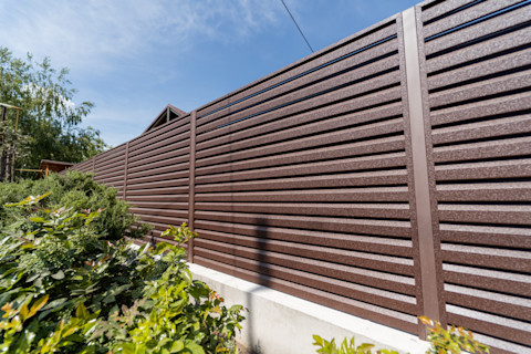 Prefab wooden fence panels are arranged horizontally. The wood has a natural finish and clean construction.