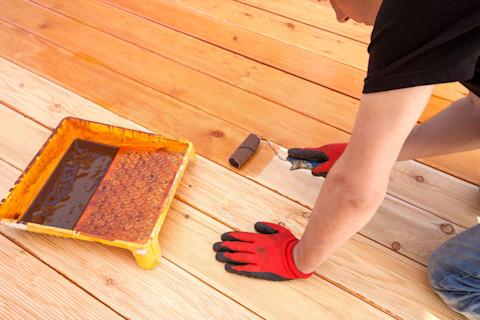 Using a roller brush to stain a deck.