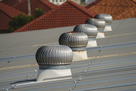 Roofing contractor inspecting house roof with ladder and safety helmet