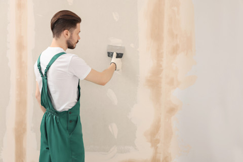 A man is installing drywall into a new home.