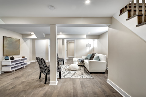 Wide shot of a finished basement with a black stone fireplace.