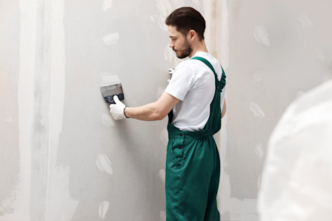 A man is installing drywall into a new home.