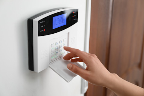 This image shows a person pressing the buttons on an electric security alarm keypad.