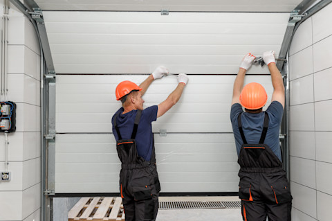 Two workers install an automatic garage door.