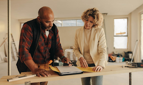 Contractor and client discussing home renovation project details and costs. Professional consultation on house renovation pricing. Planning and budgeting for a complete home remodeling.