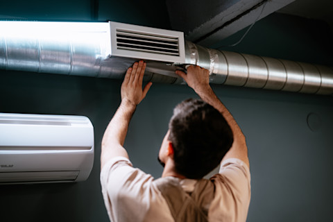 A tradesperson is clearing out an air duct.