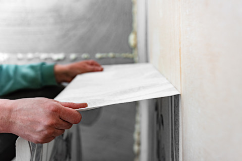 Closeup side angle of someone pulling wallpaper off the wall.