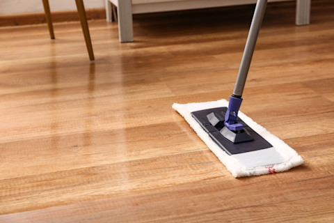 Closeup of a mop being used to clean wooden laminate flooring