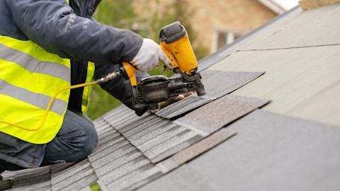 This image shows a roofer installing roofing materials on a roof.